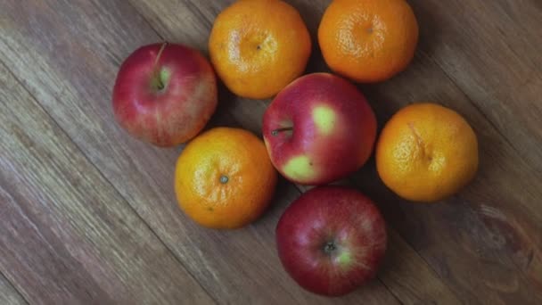 木製の背景に回転する3つの赤いリンゴとオレンジみかんの美しい景色 — ストック動画
