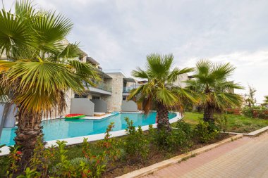 Yeşil bitkiler arasında havuzlu modern otelin güzel manzarası. Yunanistan.