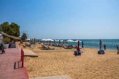 Boş güneşlik ve şemsiyeleri olan Yunanistan 'ın muhteşem beyaz kumlu plajı. Turkuaz deniz suyu ve mavi gökyüzü. Yunanistan. 