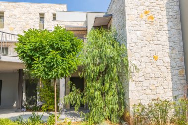 Önünde yeşil ağaçlar ve bitkiler olan modern binanın güzel dış görünüşü. Yunanistan. 