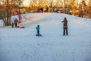 Güneşli, soğuk kış gününde insanların açık hava oyun parkındaki güzel manzarası. İsveç. Uppsala. 12.25.2021.