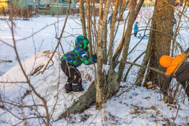 Karlı ormanda oynayan, renkli, sıcak kış kıyafetleri giymiş iki çocuğun güzel manzarası. İsveç. 