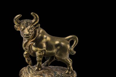 Siyah arka planda izole edilmiş Taurus sığır işaretinin bronz figürünün yakın görüntüsü.