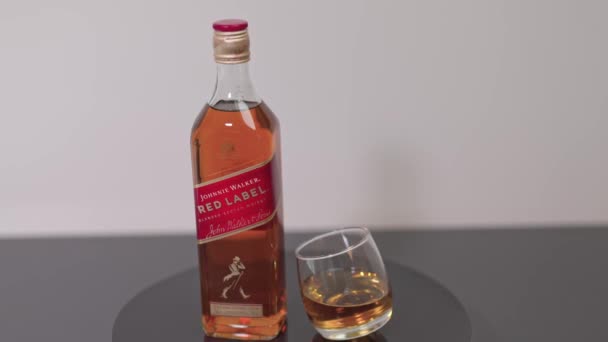 Blick Auf Johnnie Walker Red Label Whiskeyflasche Und Gefülltes Whiskeyglas — Stockvideo