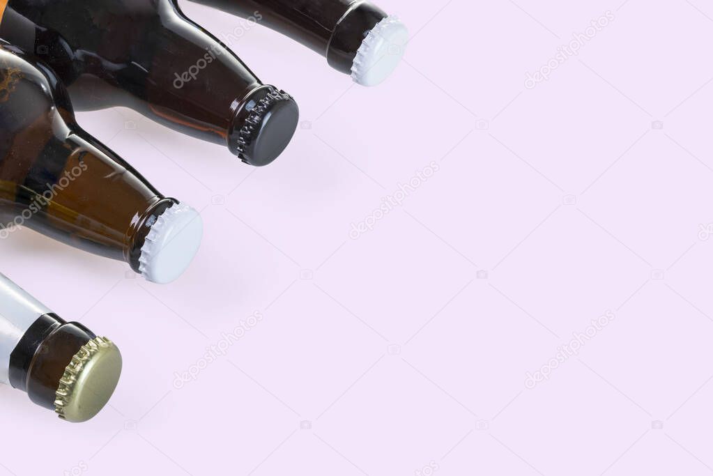 View of various grade beer bottles with metal caps on pink background.
