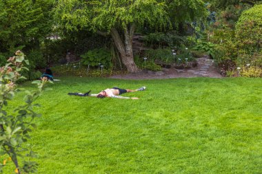 Beautiful view of man relaxing on green grass after running on warm summer day. Sweden. 