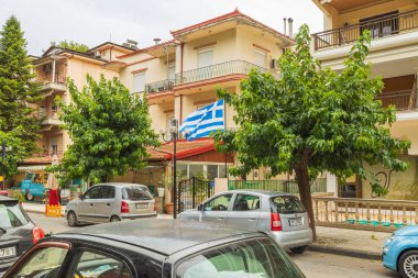 Beautiful view of one of streets of Greece with Greece flag, villas and cars on background. Greece. Europa. 09.20.2021.