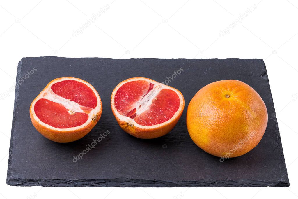 Close up view of cut and whole grapefruit isolated on black cutting board.