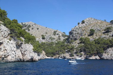 Dağ adasının arka planındaki beyaz motorlu teknenin güzel manzarası. İspanya. 