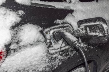 Soğuk kış arka planında elektrik kablosuna bağlı elektrikli araba görüntüsü. İsveç.