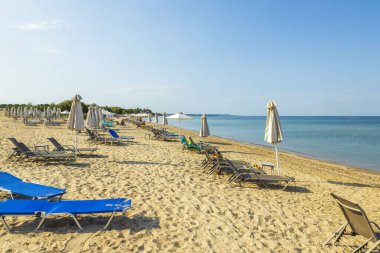 Boş güneş yataklarının güzel manzarası kumsalda kapalı güneş şemsiyelerini sona erdirir. Yunanistan. 