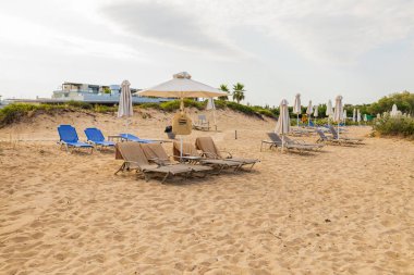 Boş şemsiyeleri ve şezlongları olan terk edilmiş plaj manzarası. Yunanistan. 