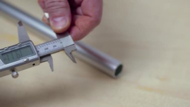 Elektronik kalibreli alüminyum boru ölçen bir adamın yakın çekim görüntüsü. İsveç.