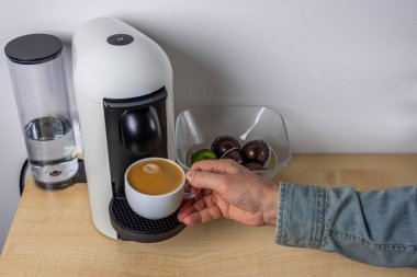 Kapsül kahve makinesinden bir kupa kahve alan erkeklerin yakın görüntüsü. İsveç.