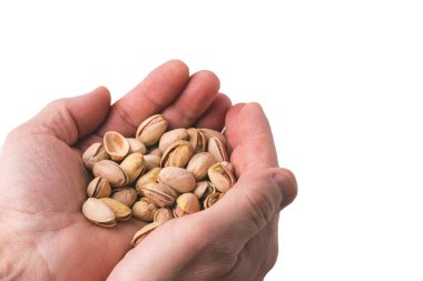 Beyaz arka planda izole edilmiş bir avuç şam fıstığını tutan kişinin ellerine yakından bakın. İsveç.