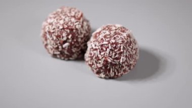 Gri arkaplanda Hindistan cevizi taneleri olan iki çikolatalı brownie 'nin yakın görüntüsü.