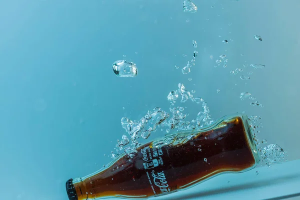 Close View Bottle Coca Cola Falling Water Isolation Blue Background — Stock Photo, Image