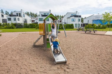 Güneşli bir yaz gününde, köyün oyun alanında oynayan çocukların güzel manzarası. İsveç. 