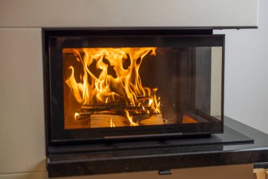 Modern evin oturma odasındaki şöminede yanan odunun güzel manzarası. İsveç.