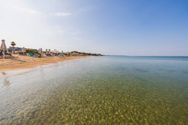 Güneşli yataklı güzel bir sahil manzarası, beyaz kum kumu ve Akdeniz 'in turkuaz sakin suları. Yunanistan.