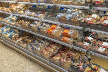 Süpermarkette raflarda duran plastik poşetlere doldurulmuş çeşitli ekmeklerle rafları kapatın. İsveç. Uppsala. 04.28.2022.