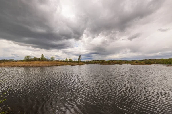 Bulutlu bir bahar gününde fırtına bulutlarına karşı güzel bir göl manzarası. İsveç.