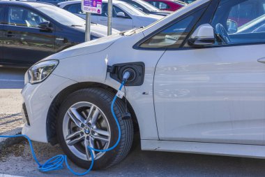 Elektrikli taşıt şarj istasyonundan BMW kablosuna bağlı kabloyu kapat. İsveç. Uppsala. 05.23.2022.