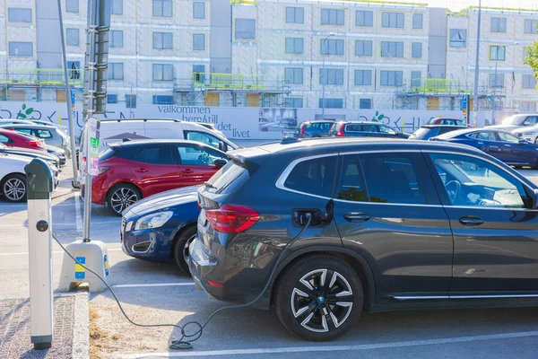 Elektrikli taşıt şarj istasyonundan siyah BMW 'ye bağlı kablo görüntüsü. İsveç. Uppsala. 05.23.2022.