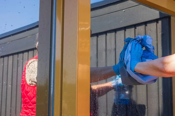 Evin penceresini temizleyen kadının yakın görüntüsü. İsveç.