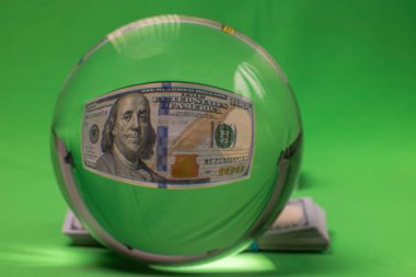 Yeşil arka planda 100 dolarlık banknotla kristal kürenin makro görüntüsü. İsveç