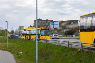 Uppsala manzara arka planındaki sarı şehir otobüslerinin yakın görüntüsü. İsveç. Uppsala. 06.19.2022.