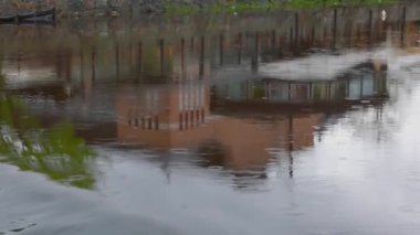 Şehir merkezindeki yağmur sırasında evlerin yansımasıyla güzel bir nehir manzarası. İsveç.
