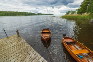Güzel bir göl manzarası var. Rıhtımda iki tekne var. Suyun arka planında. İsveç.