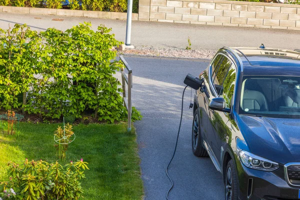 View of private parking of house with electric car charging from charging station. Sweden.