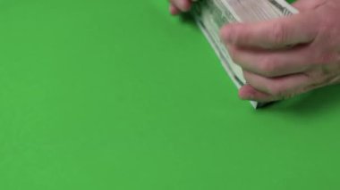 Yeşil arka planda elle izole edilmiş dolar banknotlarını sayan adama yakından bakın. İsveç. 