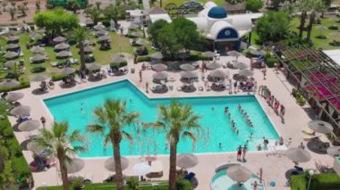 İnsanların su aerobiği yaptığı yüzme havuzlu güzel bir otel manzarası. Rodos. Yunanistan. 07.15.2022.