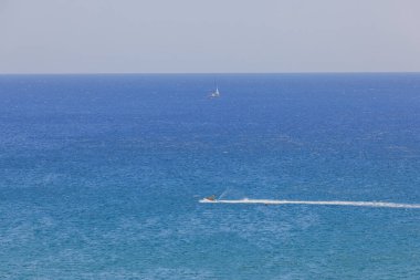 Beautiful view of Mediterranean sea with people riding water scooter. 