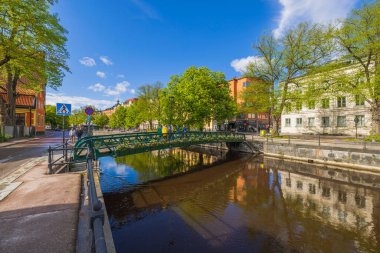 Kenarlarında renkli çiçeklerle süslenmiş küçük köprüyle güzel bir şehir manzarası. İsveç. 07.25.2022.