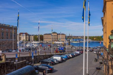 Royal Palace yakınlarındaki meydandaki otopark manzarası ve Stockholm şehir merkezindeki rıhtımda İsveç ve Finlandiya bayrakları. İsveç. Stockholm. 05.18.2022.