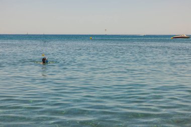 Mavi deniz suyu yüzeyinde şnorkel maskeli bir adam görülüyor. Yunanistan. 