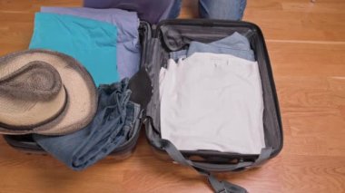 View of man packing clothes into suitcase for tourist trip. Sweden.