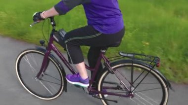 View of woman on bicycle moving on small road on beautiful countryside landscape background. Sweden. Uppsala. 08.05.2022.