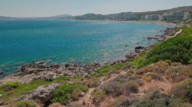 Beautiful view of rocky coast in Mediterranean sea against backdrop of hotels with sandy beaches. Greece.
