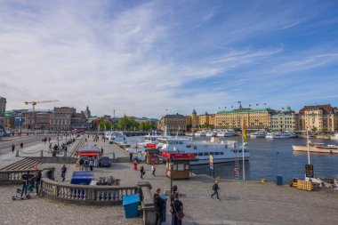 Beautiful view of people and boats on pier in center of Stockholm on bright day. Sweden. Stockholm. 05.18.2022.