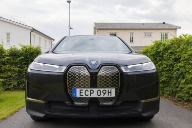 Close up view of new BMW IX40 electric car in villa's private parking lot on cloudy summer day. Sweden. 08.18.2022.