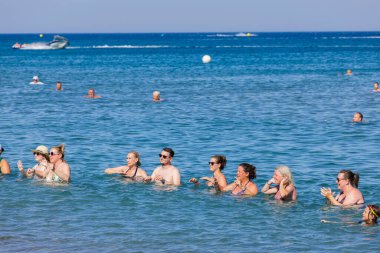 View of group of tourists doing water dancing in on coastline of Mediterranean sea. Rhodes. Greece. 07.15.2022. 