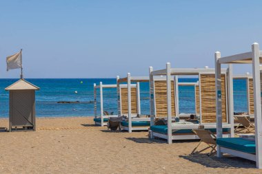 Beautiful view of sand beach on sea coastline with comfortable sun beds for hotel tourists. Rhodes. Greece.