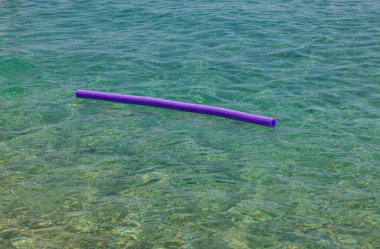 Close up view of swimming noodle ad assistant  on water surface. Greece