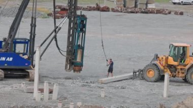  View of process of driving concrete piles with pile driver machine into ground at construction site. Sweden. Enkoping. 05.08.2022