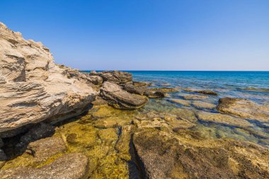 Beautiful view of rocky coastline. Blue sea water and sky merg at horizon. Greece. 